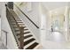 Elegant staircase with dark wood steps and iron railings leads to a bright hallway at 1796 Tonka Ter, Wesley Chapel, FL 33543