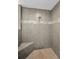 Close-up of the stylish gray tiled shower with a built-in corner seat and decorative accent at 19519 Gulf Blvd # 203, Indian Shores, FL 33785