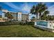 View of the community signage with lush landscaping and a glimpse of the condo building at 19519 Gulf Blvd # 203, Indian Shores, FL 33785