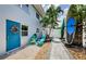 Inviting exterior featuring a blue door, tropical landscaping, and colorful Adirondack chairs at 2186 Edythe Dr # 11, Dunedin, FL 34698