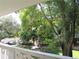 Balcony view overlooking green lawns, mature trees, and parked cars at 2630 Pearce Dr # 208, Clearwater, FL 33764
