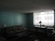 Living room features a glass coffee table and a sofa beneath sheer window curtains at 2630 Pearce Dr # 208, Clearwater, FL 33764