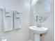 Clean powder room with modern pedestal sink, round mirror, and fresh white towels at 2746 Birchcreek Dr, Wesley Chapel, FL 33544