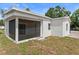 Back exterior view featuring a screened porch with new door and grassy yard at 3215 E Powhatan Ave, Tampa, FL 33610