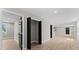 Hallway with light floors, neutral walls, and black interior doors leads to open living spaces at 3215 E Powhatan Ave, Tampa, FL 33610