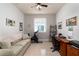 Home office featuring a beige sofa, a desk, a spin bike and neutral-colored walls with decorative artwork at 3727 Wild Blossom Pl, Parrish, FL 34219