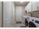 Well-lit laundry room featuring a washer, dryer, sink, white cabinets, and durable wood-look floors at 3727 Wild Blossom Pl, Parrish, FL 34219
