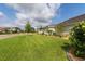 Side yard featuring lush green grass, palm trees and shrubs, and a home exterior in the background at 3727 Wild Blossom Pl, Parrish, FL 34219