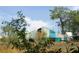 The blue barn sits in a field with some foliage partially in the foreground at 3940 E Knights Griffin Rd, Plant City, FL 33565