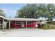 Charming single-story red house with a covered parking area and an American flag at 3940 E Knights Griffin Rd, Plant City, FL 33565