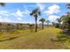 Exterior view of community and lake featuring palm trees, blue skies, and green grass at 402 Laurel Lake Dr # 104, Venice, FL 34292