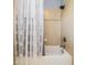 Well-lit bathroom featuring a modern shower with beige tile and a patterned shower curtain at 4094 Windcrest Dr, Wesley Chapel, FL 33544
