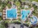 Aerial view of sparkling community pools, slide, cabanas and lush landscaping at 4094 Windcrest Dr, Wesley Chapel, FL 33544