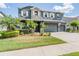 Two-story home with stone accents, a three-car garage, and mature landscaping at 4094 Windcrest Dr, Wesley Chapel, FL 33544