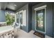 Inviting front porch with stone accents, white chairs, and a decorative glass front door at 4094 Windcrest Dr, Wesley Chapel, FL 33544