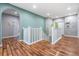 Upstairs hallway with wood floors, white railing, and access to multiple rooms at 4094 Windcrest Dr, Wesley Chapel, FL 33544