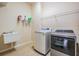 Functional laundry room with a utility sink, modern washer and dryer, and convenient wire shelving at 4094 Windcrest Dr, Wesley Chapel, FL 33544
