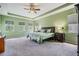 Spacious main bedroom with large windows, tray ceilings, ceiling fan, and stylish decor at 4094 Windcrest Dr, Wesley Chapel, FL 33544