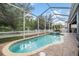 A sparkling blue pool and spa are enclosed in a screened patio with a white picket fence at 4094 Windcrest Dr, Wesley Chapel, FL 33544