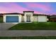 Beautiful home at dusk, featuring a blue garage door, modern design, and lush green lawn at 4260 Baudelaire Ct, Brooksville, FL 34604