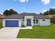 Beautiful, modern home with a blue garage door and a well-manicured lawn at 4260 Baudelaire Ct, Brooksville, FL 34604
