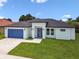 A bright home with a modern exterior, a well-kept lawn, and a vibrant blue garage door at 4260 Baudelaire Ct, Brooksville, FL 34604