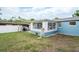 Exterior view of backyard featuring a covered patio, grill, and a light blue building addition with many windows at 4545 Annette St, New Port Richey, FL 34652