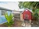 Close up view of backyard featuring a chicken coop, tropical foliage, and part of the light blue home at 4545 Annette St, New Port Richey, FL 34652