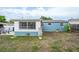 Side view of backyard featuring a building addition with many windows, a light blue house and green foliage at 4545 Annette St, New Port Richey, FL 34652