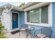 Welcoming blue front door with cozy seating area, table, and manicured landscaping enhance curb appeal at 4545 Annette St, New Port Richey, FL 34652