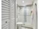 Bright bathroom featuring a shower with glass doors and white tile plus a fresh white robe hanging nearby at 500 Treasure Island Cswy # 607, Treasure Island, FL 33706