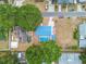 An aerial view of the backyard with a blue roofed house, pool, and driveway, surrounded by trees at 504 E Lee St, Plant City, FL 33563