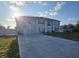 Bright blue two-story house featuring a wide driveway, a manicured lawn, and solar panels at 5391 Baldock Ave, Spring Hill, FL 34608
