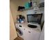 Laundry room with open-lid top-loading washer and front-loading dryer and wire shelf at 5391 Baldock Ave, Spring Hill, FL 34608