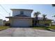 Two-story home featuring an attached two-car garage, palm trees, and a well-maintained front yard at 5930 Bahama N Way, St Pete Beach, FL 33706