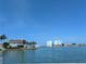 Beautiful waterfront view of a charming two-story white home with palm trees and nearby condo buildings at 5930 Bahama N Way, St Pete Beach, FL 33706