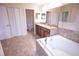 Bright bathroom featuring a soaking tub, double vanity with granite countertop, and tiled floor at 621 Washita Stone Dr, Ruskin, FL 33570