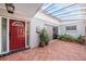Inviting front porch with red door, terracotta tile, decorative plants, and unique water feature at 6811 N Himes Ave, Tampa, FL 33614