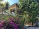 Charming two-story home featuring a covered porch, lush landscaping, and vibrant purple flowers at 943 7Th N St, St Petersburg, FL 33701