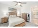 Relaxing bedroom with a ceiling fan, wooden furniture, and view of a modern bathroom at 10418 Spring Tide Way, Parrish, FL 34219