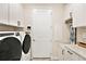 Functional laundry room with modern washer and dryer, white cabinets, and counter space at 10418 Spring Tide Way, Parrish, FL 34219