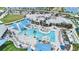 An aerial view of a resort-style pool with blue shade coverings, a clubhouse, and ample seating with palm trees at 10418 Spring Tide Way, Parrish, FL 34219