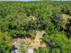 Secluded property featuring a red home nestled within lush green trees and a winding driveway at 11120 Lu Wista Ln, Brooksville, FL 34601
