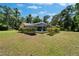 A spacious green lawn and backyard view of a screened-in pool and neutral colored home at 11120 Lu Wista Ln, Brooksville, FL 34601