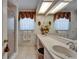 Bright bathroom featuring dual sinks, decorative wallpaper, vanity with a large mirror and a stand up shower at 11120 Lu Wista Ln, Brooksville, FL 34601