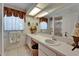 Bright bathroom featuring dual sinks, decorative wallpaper, vanity with a large mirror and great lighting at 11120 Lu Wista Ln, Brooksville, FL 34601