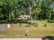A single-story home surrounded by lush greenery and mature trees, showcasing the expansive front yard at 11120 Lu Wista Ln, Brooksville, FL 34601