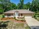 Charming single-story home featuring a manicured lawn, mature trees, and a welcoming two-car garage at 11120 Lu Wista Ln, Brooksville, FL 34601