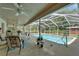 Relaxing outdoor pool area featuring a screened-in pool with chairs, tables, plants and a ceiling fan at 11120 Lu Wista Ln, Brooksville, FL 34601
