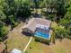 Drone shot showcasing a backyard screened-in pool and green landscaping of a neutral house at 11120 Lu Wista Ln, Brooksville, FL 34601